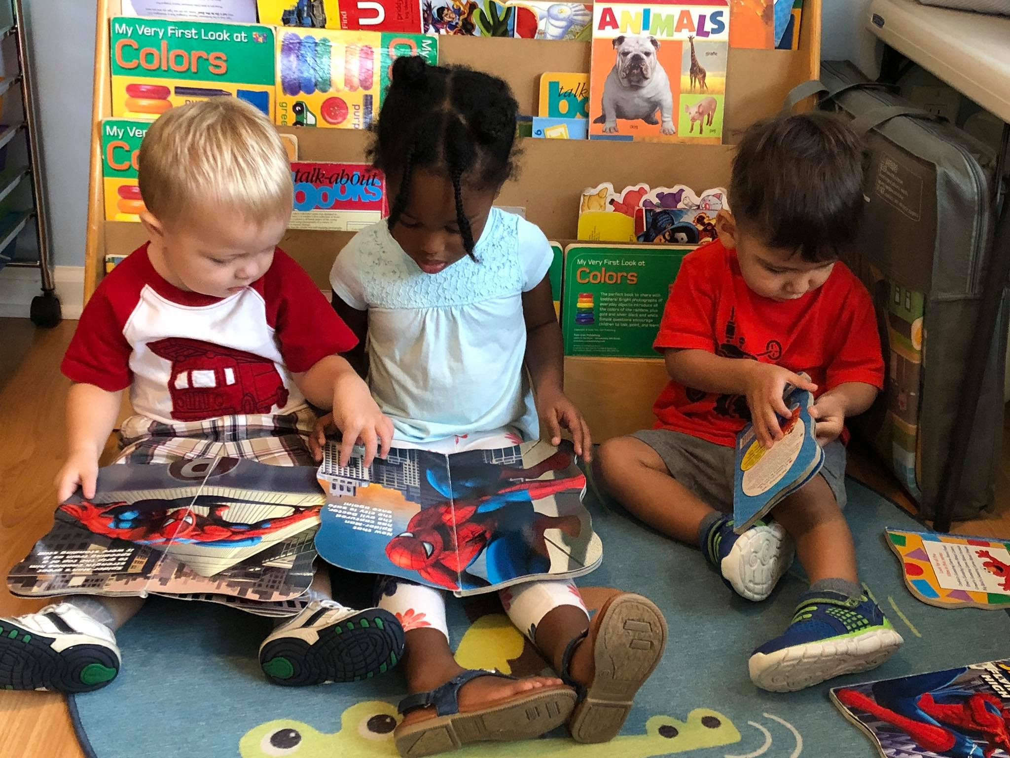 Three young children sitting together reading colorful books